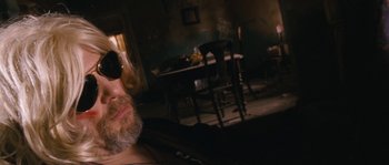 Movie still from “Tideland” (2005), directed by Terry Gilliam – A man with a beard and sunglasses sitting in front of a table; Close Up shot, Low angle