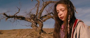 Movie still from “Tideland” (2005), directed by Terry Gilliam – A young girl standing in front of a dead tree; Close Up shot, Low angle