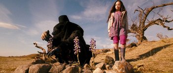 Movie still from “Tideland” (2005), directed by Terry Gilliam – A young girl standing next to an older woman; Wide shot, Low angle