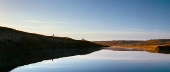 Movie still from “Tideland” (2005), directed by Terry Gilliam – A person standing on a hill near a body of water; Extreme Wide shot, Low angle