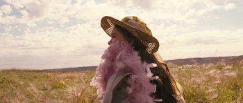 Movie still from “Tideland” (2005), directed by Terry Gilliam – A woman wearing a hat and a pink feather boa; Close Up shot, Over the shoulder angle