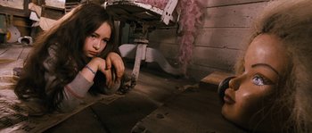 Movie still from “Tideland” (2005), directed by Terry Gilliam – A girl sitting on the ground next to a chair; Medium shot, High angle
