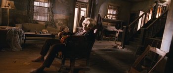 Movie still from “Tideland” (2005), directed by Terry Gilliam – A man sitting in a chair in an abandoned room; Wide shot, Low angle