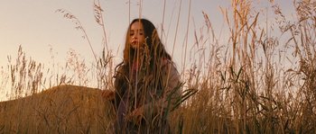 Movie still from “Tideland” (2005), directed by Terry Gilliam – A woman sitting in tall grass in a field; Medium shot, Low angle