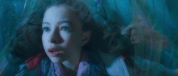 Movie still from “Tideland” (2005), directed by Terry Gilliam – A young girl with blue eyes is laying in the water; Close Up shot, Overhead angle