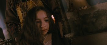 Movie still from “Tideland” (2005), directed by Terry Gilliam – A young girl with long hair and a white shirt is holding an umbrella; Close Up shot, High angle