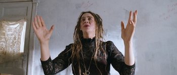 Movie still from “Tideland” (2005), directed by Terry Gilliam – A woman with dreads is holding her hands in the air; Close Up shot, Low angle