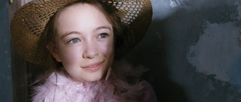 Movie still from “Tideland” (2005), directed by Terry Gilliam – A young girl wearing a pink feather boa and a straw hat; Close Up shot, High angle
