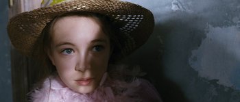 Movie still from “Tideland” (2005), directed by Terry Gilliam – A young girl wearing a straw hat and a pink dress; Close Up shot, High angle