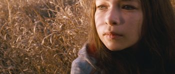Movie still from “Tideland” (2005), directed by Terry Gilliam – A young woman's face in front of a field of tall grass; Close Up shot, High angle