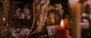 Movie still from “Tideland” (2005), directed by Terry Gilliam – A woman wearing a wreath looking at a candle; Close Up shot, Over the shoulder angle