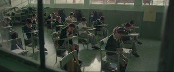 Movie still from “Tigers Are Not Afraid” (2017), directed by Issa López – A group of people sitting at desks in a room; Wide shot, High angle