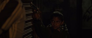 Movie still from “Tigers Are Not Afraid” (2017), directed by Issa López – A young boy holding a toy gun in a dark room; Medium shot, Over the shoulder angle