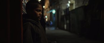 Movie still from “Tigers Are Not Afraid” (2017), directed by Issa López – A young boy standing in the dark on the street; Close Up shot, Over the shoulder angle