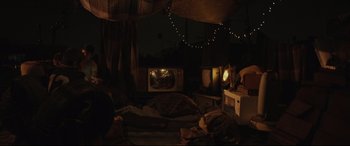 Movie still from “Tigers Are Not Afraid” (2017), directed by Issa López – An old tv in the dark room; Wide shot, High angle