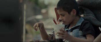 Movie still from “Tigers Are Not Afraid” (2017), directed by Issa López – A young boy holding a cup of hot sauce; Close Up shot, Over the shoulder angle