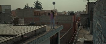 Movie still from “Tigers Are Not Afraid” (2017), directed by Issa López – A woman standing on top of a building on a roof; Wide shot, Low angle
