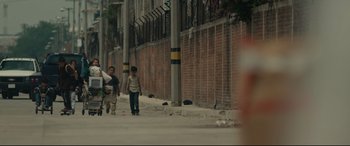 Movie still from “Tigers Are Not Afraid” (2017), directed by Issa López – A group of people walking down a sidewalk; Extreme Wide shot, Low angle