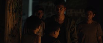 Movie still from “Tigers Are Not Afraid” (2017), directed by Issa López – A group of young men standing next to each other in the dark; Medium shot, Over the shoulder angle