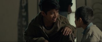 Movie still from “Tigers Are Not Afraid” (2017), directed by Issa López – A young man sitting on the ground in a room; Close Up shot, Over the shoulder angle