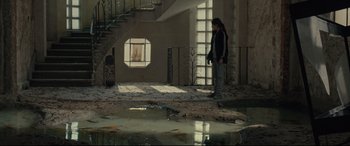 Movie still from “Tigers Are Not Afraid” (2017), directed by Issa López – A person standing in a room next to a staircase; Wide shot, High angle