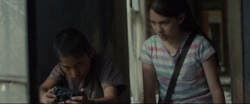 Movie still from “Tigers Are Not Afraid” (2017), directed by Issa López – A boy and a girl looking at a cell phone; Medium shot, Over the shoulder angle