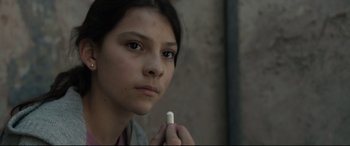 Movie still from “Tigers Are Not Afraid” (2017), directed by Issa López – A woman holding a pill in her hand; Close Up shot, Over the shoulder angle