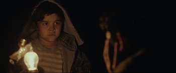 Movie still from “Tigers Are Not Afraid” (2017), directed by Issa López – A young boy holding a gun in a dark room; Close Up shot, Over the shoulder angle