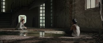Movie still from “Tigers Are Not Afraid” (2017), directed by Issa López – A person sitting on the ground near a window; Extreme Wide shot, High angle