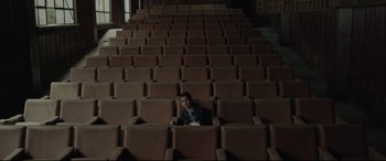 Movie still from “Tigers Are Not Afraid” (2017), directed by Issa López – A man sitting in a chair in an empty auditorium; Extreme Wide shot, High angle