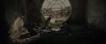 Movie still from “Tigers Are Not Afraid” (2017), directed by Issa López – A group of people sitting on the ground in front of a window; Wide shot, Low angle
