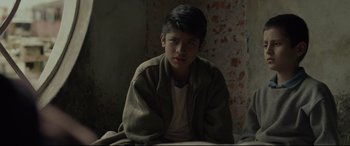 Movie still from “Tigers Are Not Afraid” (2017), directed by Issa López – A young man sitting in front of a brick wall; Close Up shot, Low angle