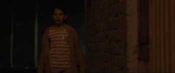 Movie still from “Tigers Are Not Afraid” (2017), directed by Issa López – A young girl standing next to a brick wall in the dark; Medium shot, Over the shoulder angle