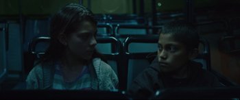 Movie still from “Tigers Are Not Afraid” (2017), directed by Issa López – Two people sitting on a bus looking at each other; Close Up shot, High angle