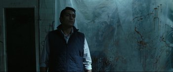 Movie still from “Tigers Are Not Afraid” (2017), directed by Issa López – A man standing in front of a wall with blood on it; Medium shot, Over the shoulder angle