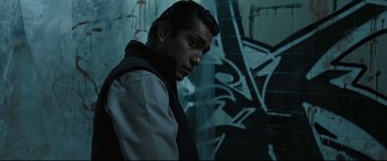 Movie still from “Tigers Are Not Afraid” (2017), directed by Issa López – A man standing in front of a wall with graffiti on it; Medium shot, Low angle