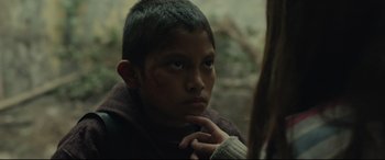 Movie still from “Tigers Are Not Afraid” (2017), directed by Issa López – A young boy looking at the camera while holding his hand up to his face; Close Up shot, Over the shoulder angle