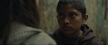 Movie still from “Tigers Are Not Afraid” (2017), directed by Issa López – A young boy looking at the camera while standing in front of a woman; Close Up shot, Over the shoulder angle