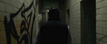 Movie still from “Tigers Are Not Afraid” (2017), directed by Issa López – A man wearing a jacket walking down a hallway; Medium shot, Over the shoulder angle