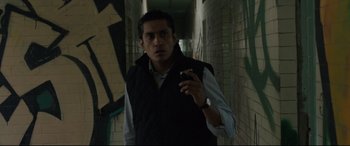 Movie still from “Tigers Are Not Afraid” (2017), directed by Issa López – A man holding a cigarette in his hand while standing in a hallway; Medium shot, Low angle