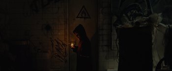 Movie still from “Tigers Are Not Afraid” (2017), directed by Issa López – A person holding a lit candle in a dark room; Wide shot, Low angle