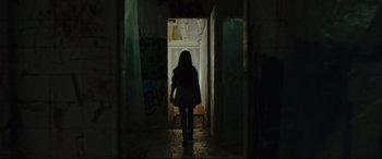 Movie still from “Tigers Are Not Afraid” (2017), directed by Issa López – A woman walking down a hallway in a dark room; Wide shot, Over the shoulder angle