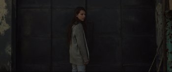 Movie still from “Tigers Are Not Afraid” (2017), directed by Issa López – A woman standing in front of a black wall; Medium shot, High angle