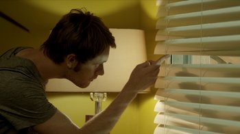Movie still from “Time Lapse” (2014), directed by Bradley King – A man is looking through a window blind; Extreme Close Up shot, Low angle