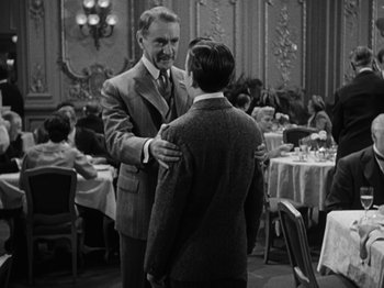 Movie still from “Titanic” (1953), directed by Jean Negulesco – A man in a suit and tie standing next to another man in a suit and tie; Medium shot, Over the shoulder angle