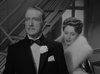 Movie still from “Titanic” (1953), directed by Jean Negulesco – An older man and a younger woman standing next to each other in front of a staircase; Medium shot, Low angle