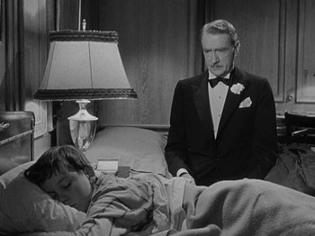 Movie still from “Titanic” (1953), directed by Jean Negulesco – An older man in a tuxedo and a young boy in a bed; Medium shot, High angle