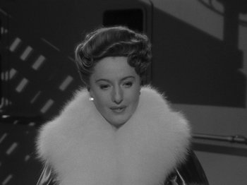 Movie still from “Titanic” (1953), directed by Jean Negulesco – A woman in a white fur coat standing in front of a building; Close Up shot, Low angle
