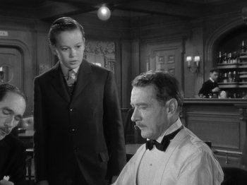 Movie still from “Titanic” (1953), directed by Jean Negulesco – A man sitting in front of another man in front of a bar; Medium shot, Over the shoulder angle