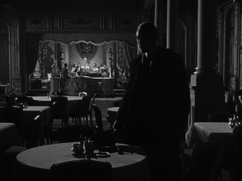Movie still from “Titanic” (1953), directed by Jean Negulesco – A black and white photo of a man standing in front of a table; Wide shot, Over the shoulder angle